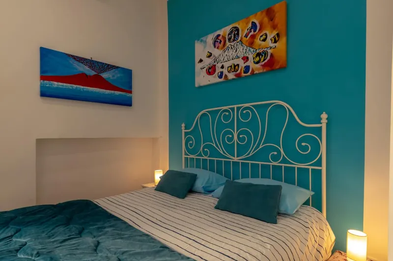 The wrought-iron double bed against the turquoise wall, with the bedside lamps lit.
