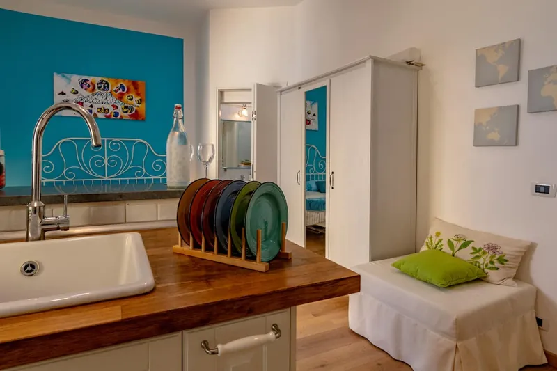The white wardrobe and the sofa bed with its green cushion, next to the sink.