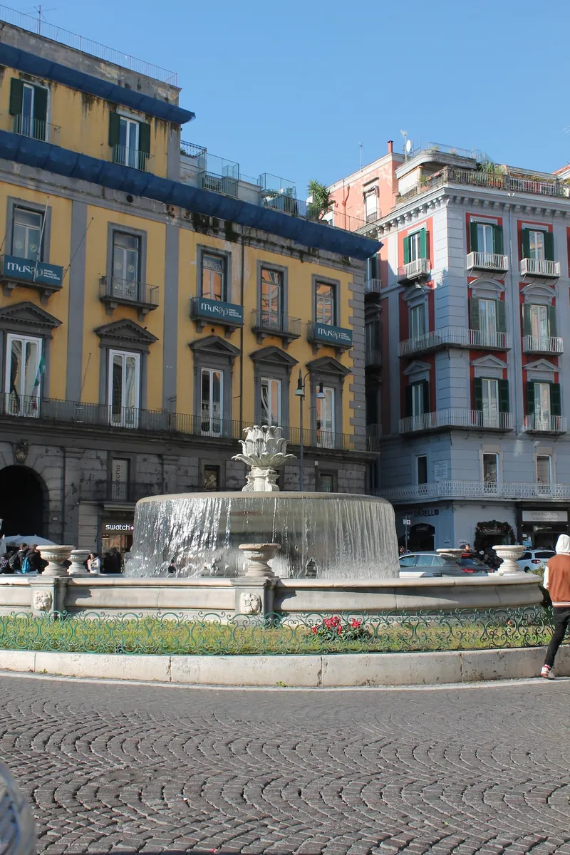 The fountain in Piazza Trieste e Trento, with its yellow and pink buildings.